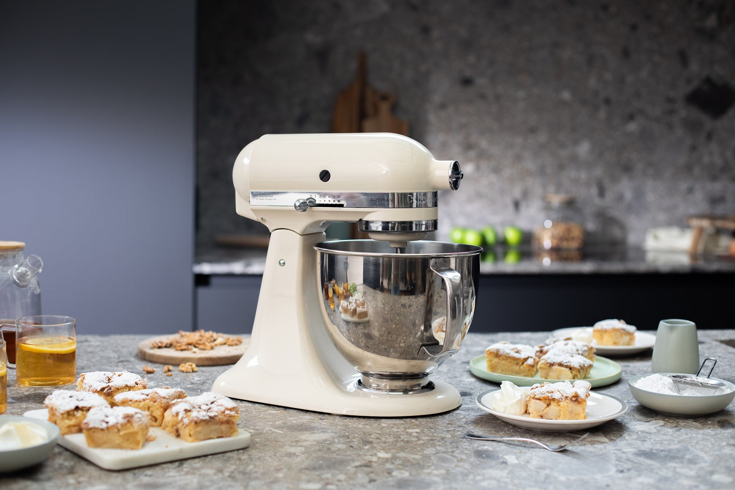 Cremefarbene KitchenAid Küchenmaschine mit eingesetzter Edelstahlschüssel, daneben mehrere Teller mit Apfelmus