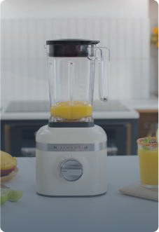 KitchenAid Standmixer K400 in Creme mit gelbem Saft im Mixbehälter auf heller Küchenplatte