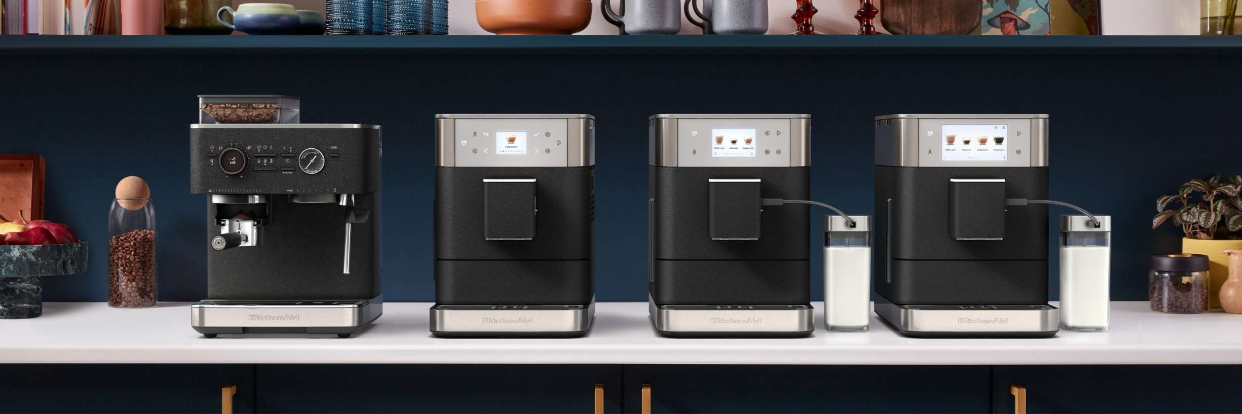 Alle Kaffeevoll- und halbautomaten der KitchenAid Espresso Collection in gusseiesen schwarz stehen nebeneinander auf einer Küchenplatte in einer blauen Küche