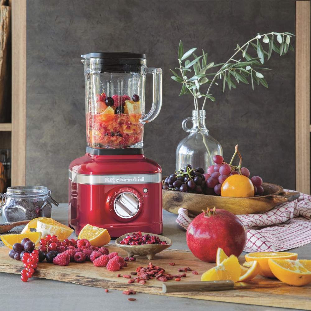 Ein Standmixer der Marke KitchenAid steht auf einem Tisch mit vielen verschiedenen Früchten