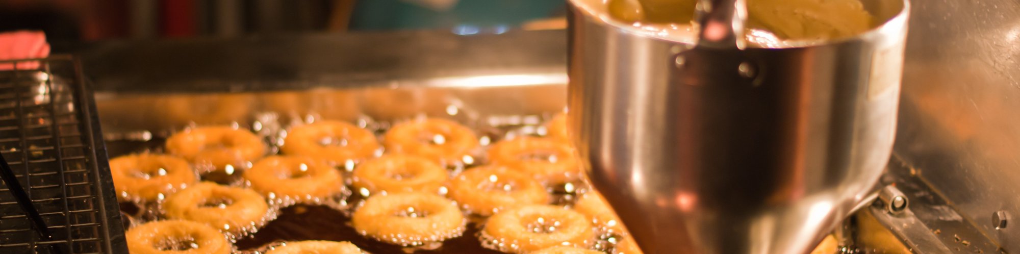 Nahaufnahme mit Blick in eine Fritteuse bei welcher mit einer Belshaw Donutanlage frische Donuts gebacken werden