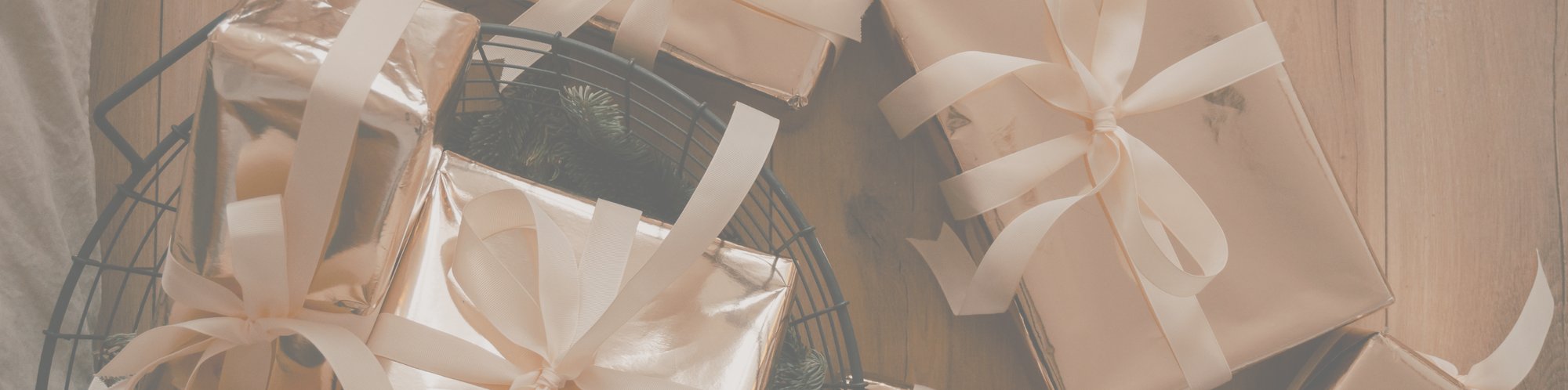 Verschiedene Geschenke, verpackt in glänzendes Geschenkpapier liegen auf einem Holzfußboden.