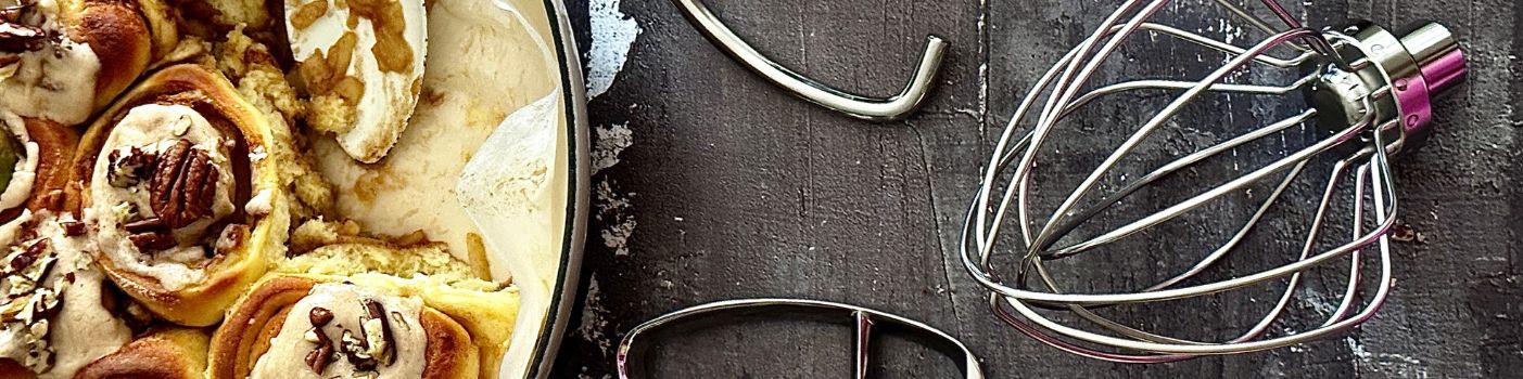 Zimtschnecken in Backform mit TschimmHook Rührbesen und Knethaken auf dunkler Arbeitsfläche.