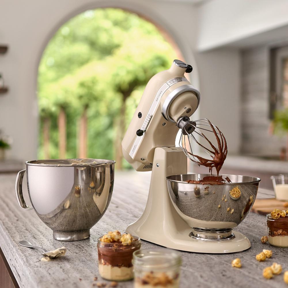 Kuechentisch mit einer KitchenAid Kuechenmaschine mit frisch angeruehrtes Tiramisu in der Schuessel. Neben der Kuechenmaschine steht eine zweite Schuessel mit weiteren Zutaten sowie kleine Gläser mit zubereiteten Tiramisu Gläser.