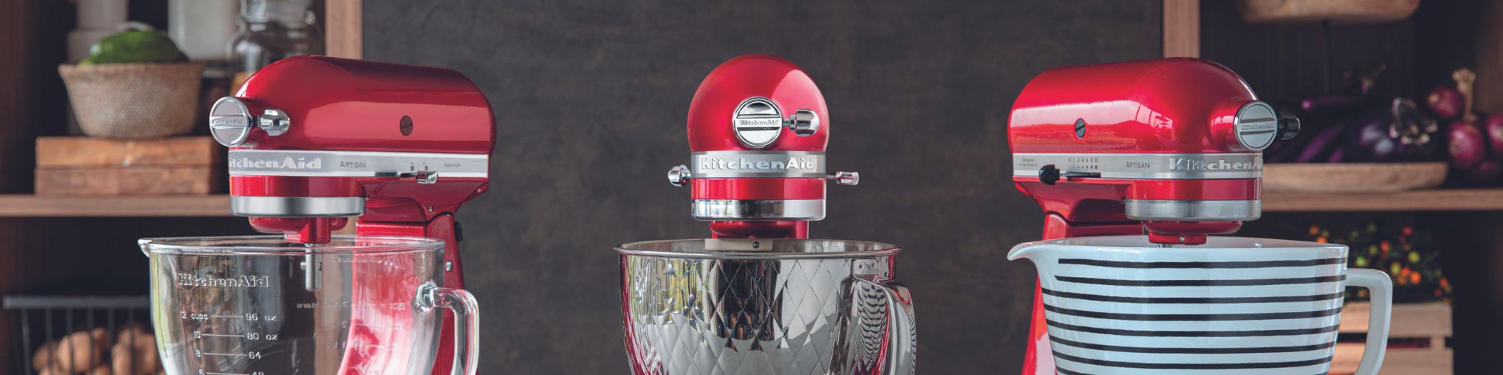 drei rote KitchenAid Küchenmaschinen nebeneinander, man sieht jeweils nur die Maschinenköpfe