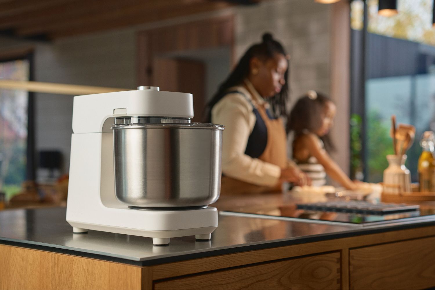 Ooni Halo Pro in weiß in einer Küche im Vordergrund, im Hintergrund backt eine Mutter mit ihrem Kind