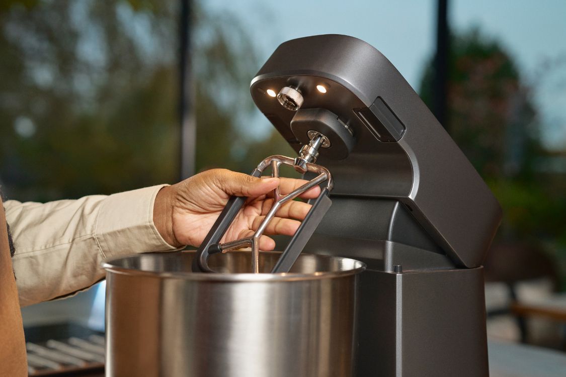 Ooni Halo Pro in schwarz mit einem eingebauten flexiblen Flachrührer, der von einer Hand gehalten wird