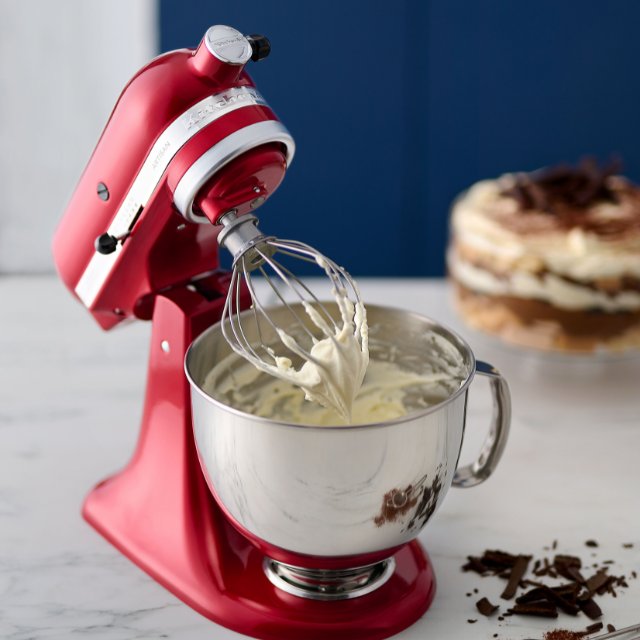 KitchenAid Kuechenmaschie steht auf einem Tisch in einer modernen Kueche. In der Schuessel befindet sich frisch angeruehrte Creme.
