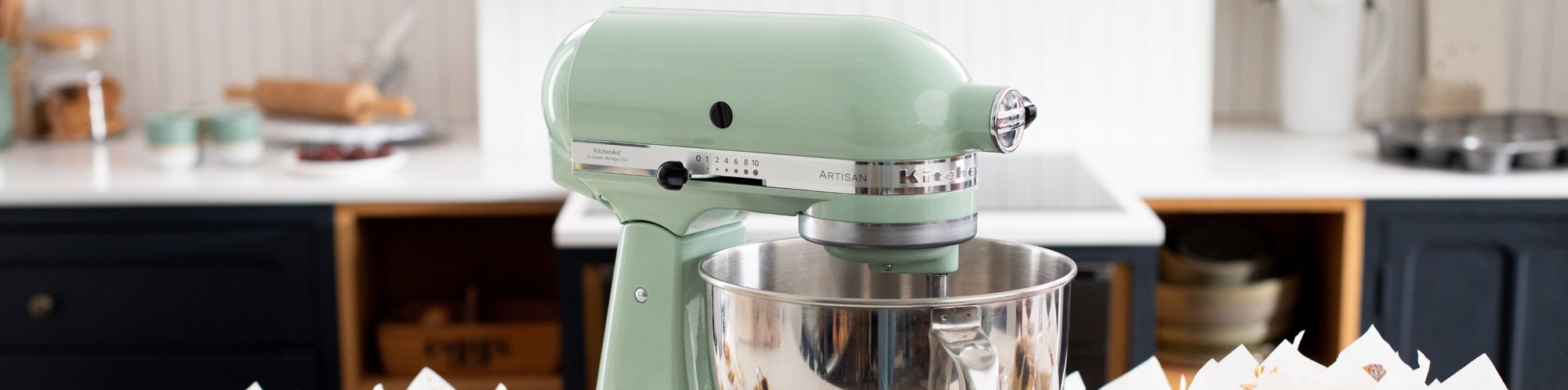 Kuechenmaschine in der Farbe Pistazie der Marke KitchenAid steht in einer modernen Kueche