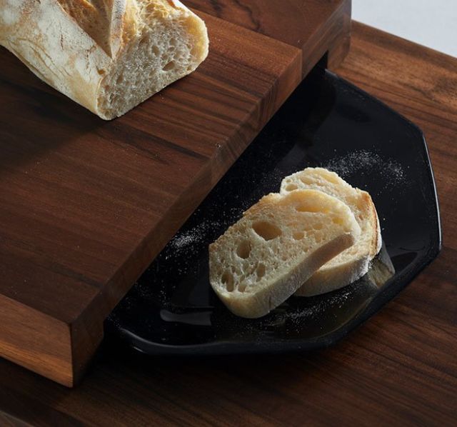 Breka Serviertisch mit einem schwarzen Keramikteller auf dem zwei geschnittene Scheiben Baguette liegen.