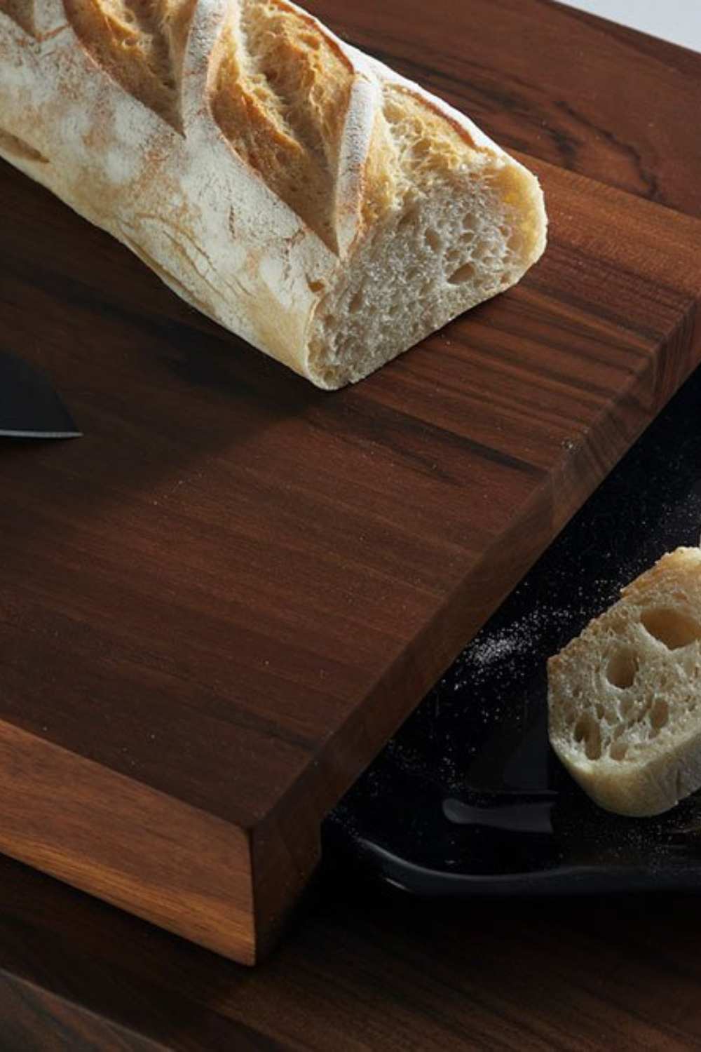 Breka Serviertisch mit einem schwarzen Keramikteller auf dem zwei geschnittene Scheiben Baguette liegen.