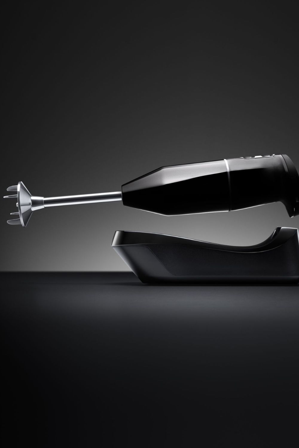 Schwarzer ESGE Zauberstab Stabmixer schwebt über der Ladestation und wird von der Seite beleuchtet.