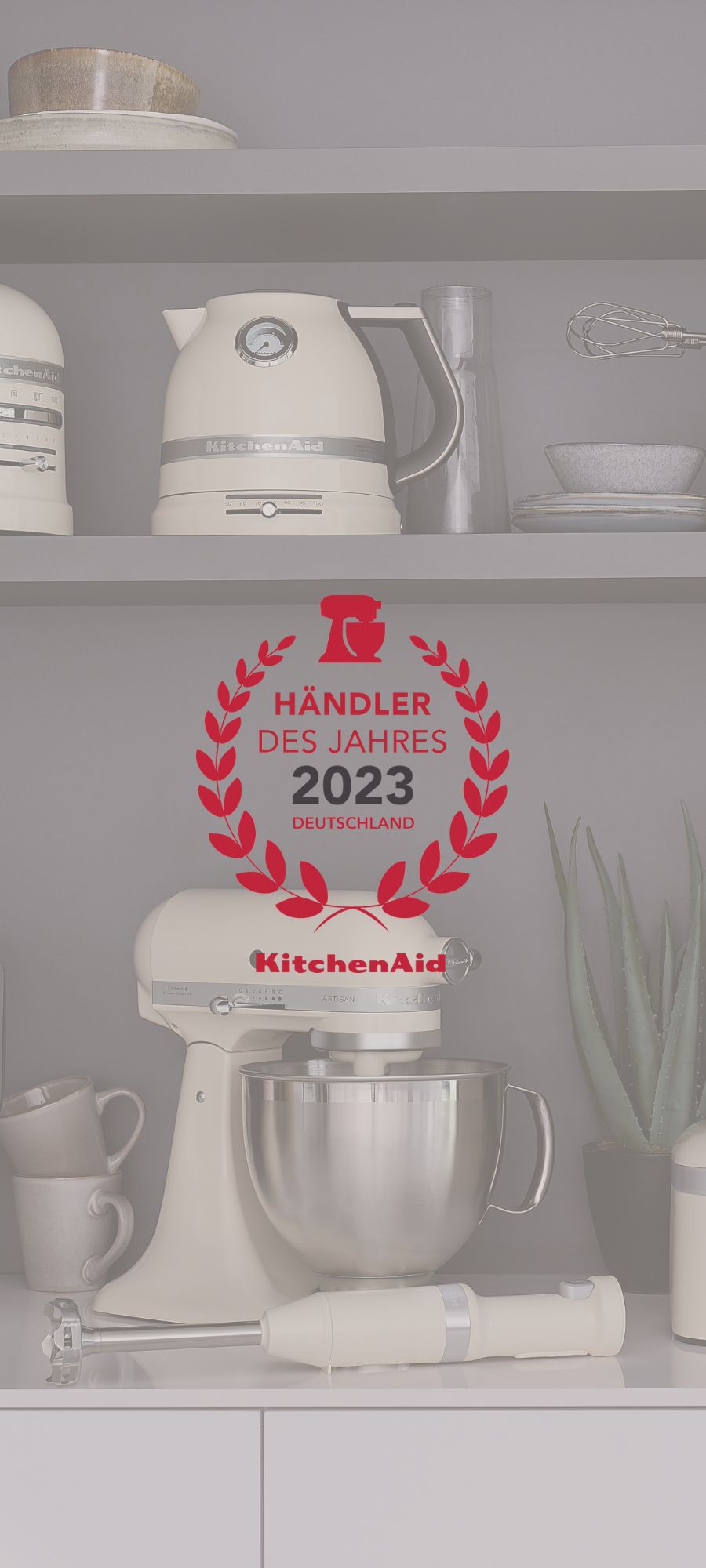 Hochkantiger Banner mit verschiedenen KitchenAid Produkten im Hintergrund und einem "KitchenAid Händler des Jahres 2023 Deutschland" Siegel