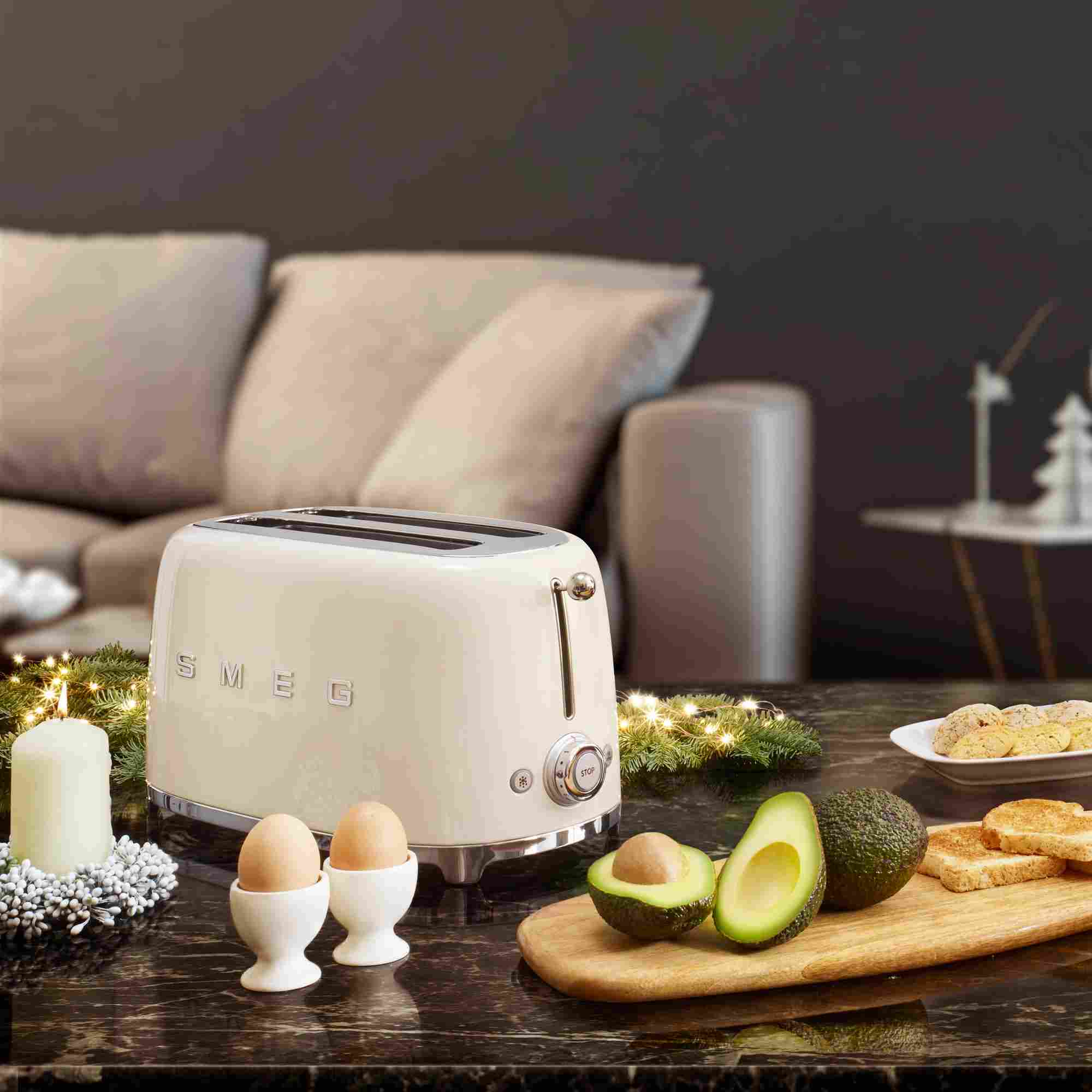 Ein gedeckter Tisch mit einem Smeg Toaster in der Farbe Creme sowie weiteren Frühstücksgegenständen.